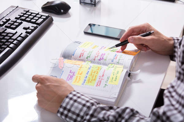 Businessperson With Mobile Phone Writing Schedule Stock photo © AndreyPopov