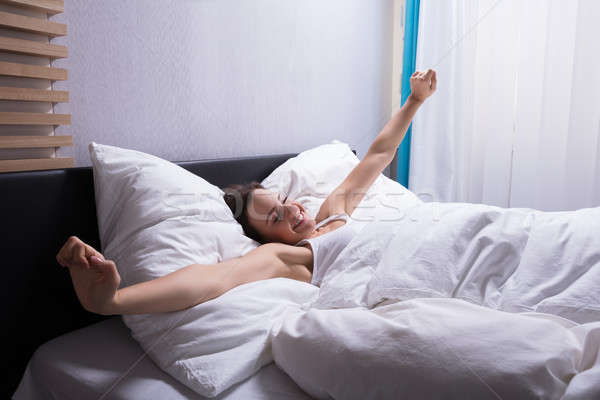 Woman Stretching Her Hands On Bed Stock photo © AndreyPopov