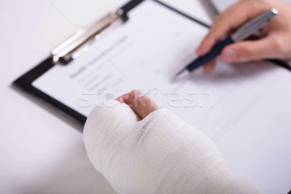 Person With Fractured Hand Filling Health Insurance Form Stock photo © AndreyPopov