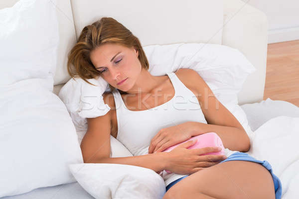 Woman With Hot Water Bag In Bed Stock photo © AndreyPopov