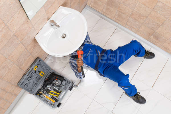 Plumber Lying On Floor Repairing Sink In Bathroom Stock photo © AndreyPopov