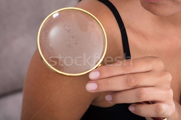 Woman Showing Skin On Shoulder Using Magnifying Glass Stock photo © AndreyPopov