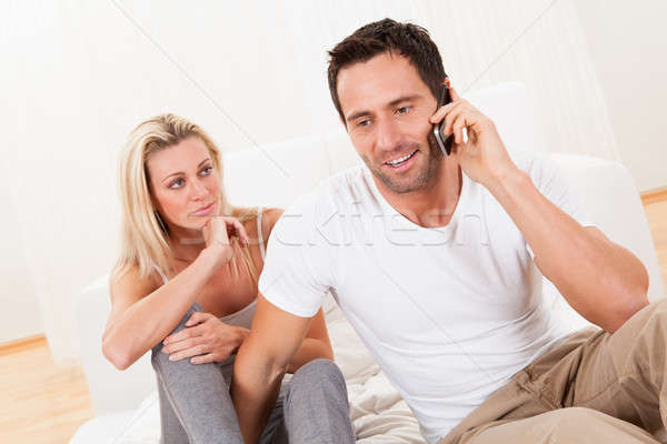 Man talking on his mobile watched by his wife Stock photo © AndreyPopov