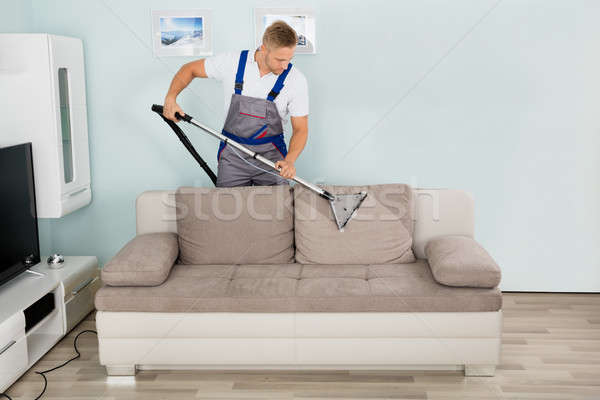 Masculin lucrător curăţenie canapea aspirator tineri Imagine de stoc © AndreyPopov
