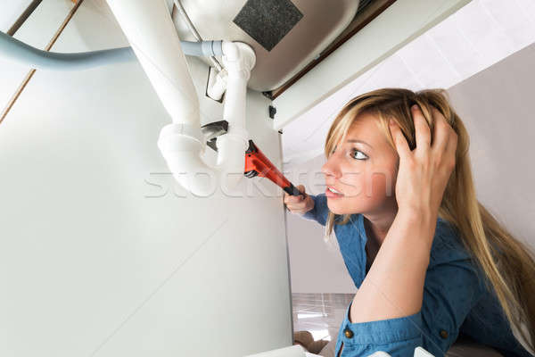 Woman Fixing Sink Pipe With Wrench In Kitchen Stock photo © AndreyPopov