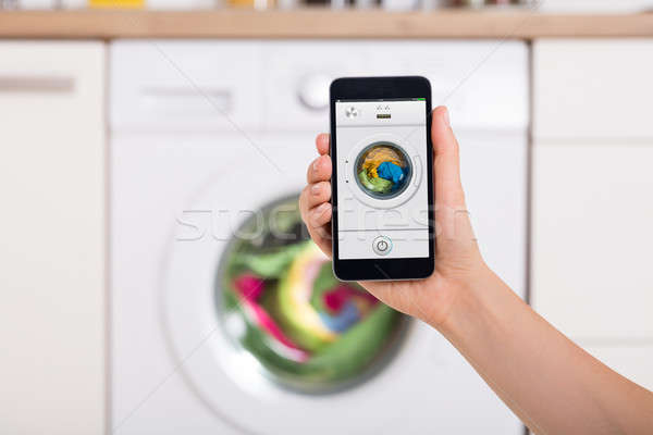 Woman Using Mobile Phone To Operate Washing Machine Stock photo © AndreyPopov