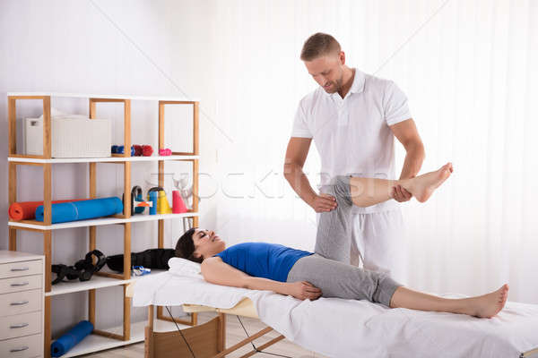 Physiotherapist Giving Leg Exercise To Female Patient Stock photo © AndreyPopov