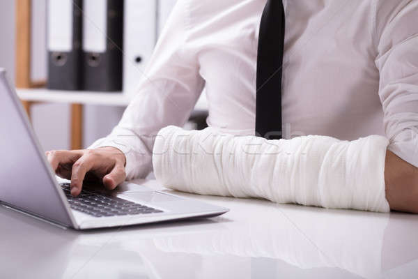 Man With Fractured Hand Using Laptop Stock photo © AndreyPopov
