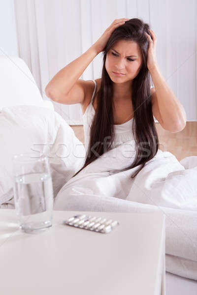 Mulher enxaqueca dor de cabeça sessão para cima cama Foto stock © AndreyPopov