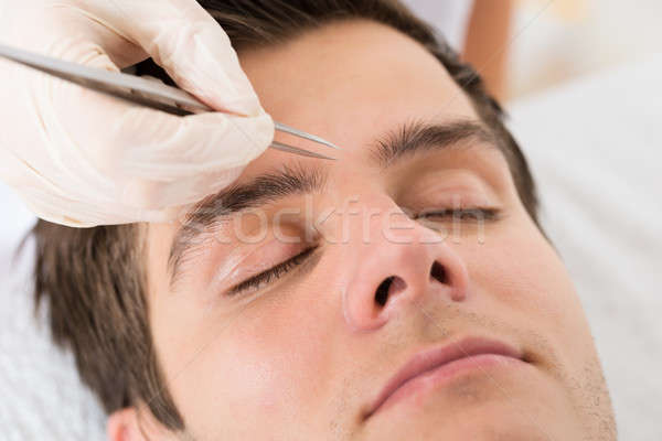 Beautician Hands Plucking Man Eyebrows With Tweezers Stock photo © AndreyPopov