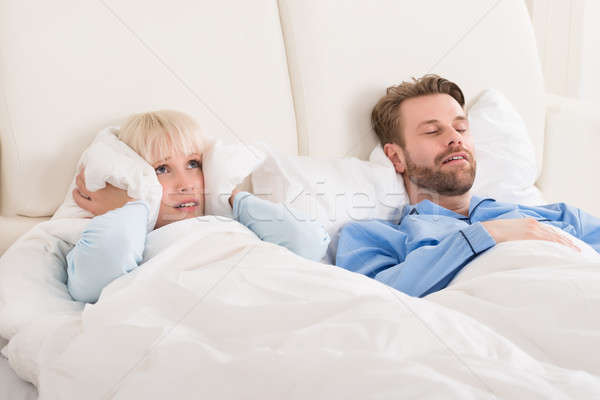 Woman Covering Ears While Man Snoring In Bed Stock photo © AndreyPopov