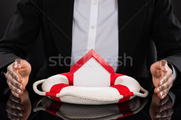 Businessperson's Hand Protecting House With Lifebelt Stock photo © AndreyPopov