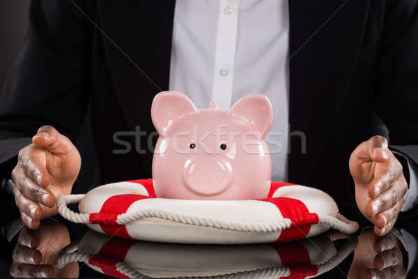 Businessperson Hand Protecting Piggybank With Lifebelt Stock photo © AndreyPopov