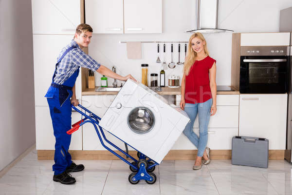 Male Worker Using Hand Truck For Carrying Washer In Kitchen Stock photo © AndreyPopov