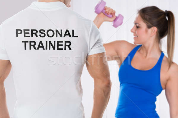 Woman Doing Exercise In Front Of Personal Trainer Stock photo © AndreyPopov