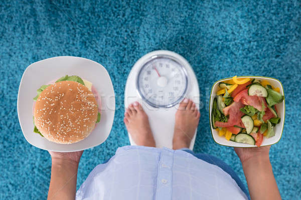 Stock photo: Person Holding Plates Of Burger And Salad