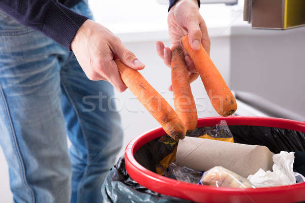 Stock photo: Person Throwing Carrot In Dustbin