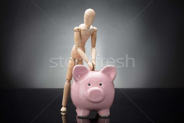 Wooden Dummy Inserting Coin In Piggy Bank Stock photo © AndreyPopov
