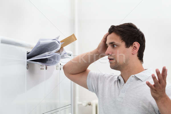 Man with hand on head in front of overloaded mailbox Stock photo © AndreyPopov