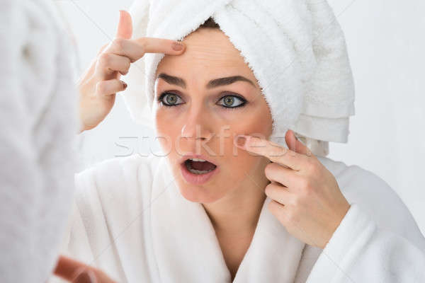 Worried Woman Looking At Pimple On Face Stock photo © AndreyPopov