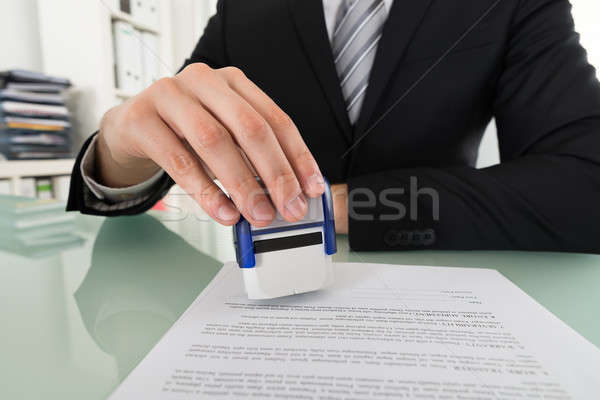 Businessman Using Stamper On Document Stock photo © AndreyPopov