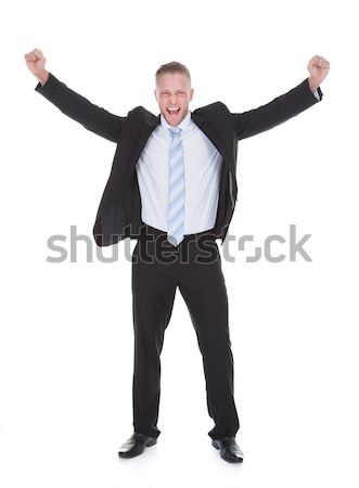 Young businessman in a suit standing cheering Stock photo © AndreyPopov