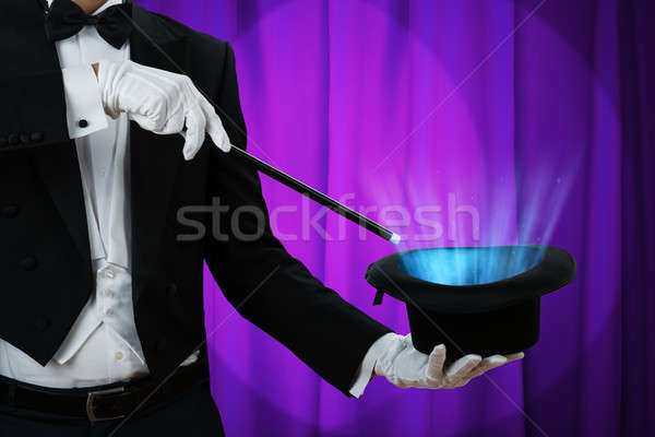 Magician Holding Wand Over Illuminated Hat Stock photo © AndreyPopov