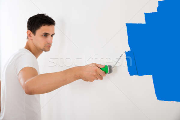 Man Painting Wall With Blue Paint Roller Stock photo © AndreyPopov
