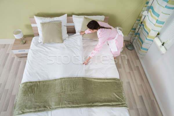 Female Housekeeper Arranging Bedsheet On Bed Stock photo © AndreyPopov