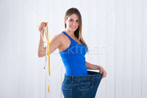Stock photo: Woman In Big Jeans Holding Measuring Tape