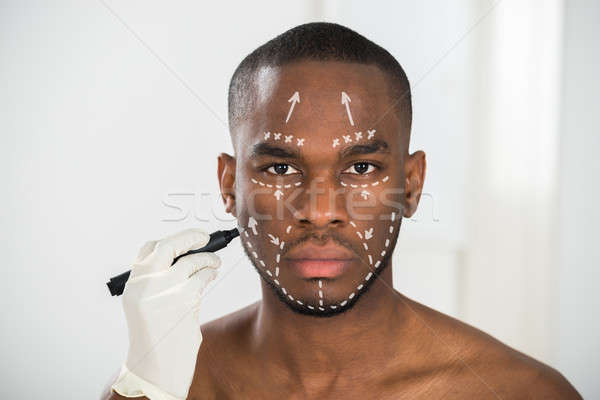 Person's Hand Drawing Correction Lines On Man's Face Stock photo © AndreyPopov
