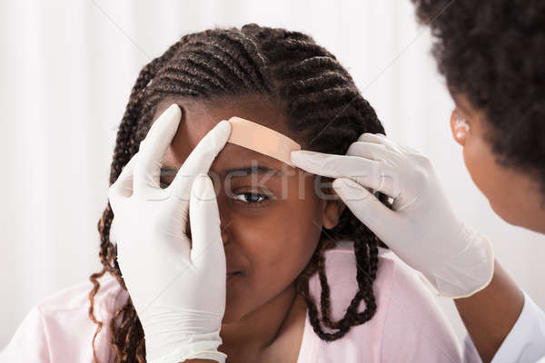 Doctor Applying Band Aid To Girl Head Stock photo © AndreyPopov