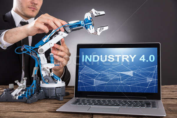 Businessman Building Robot With Laptop Showing Industry 4.0 Stock photo © AndreyPopov