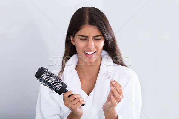 Woman In Bathrobe Holding Comb While Looking At Hair Loss Stock photo © AndreyPopov