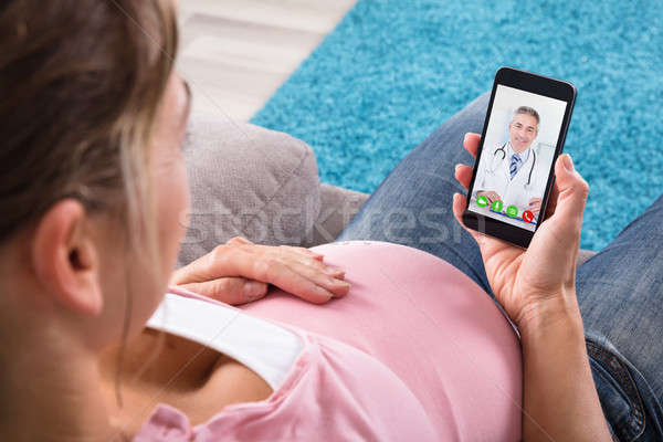 [[stock_photo]]: Femme · enceinte · séance · canapé · vidéo · médecin · téléphone · portable