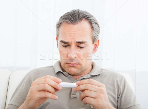 Mature sick man looking at thermometer Stock photo © AndreyPopov