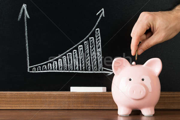 Close-up Of A Hand Putting A Coin Into Piggy Bank Stock photo © AndreyPopov