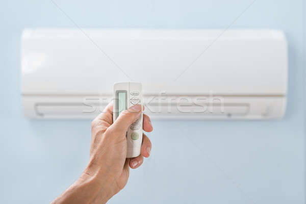 Persona mano condizionatore d'aria remote primo piano Foto d'archivio © AndreyPopov