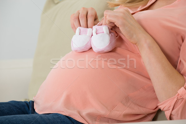 Pregnant Woman Holding Baby Shoes On Sofa Stock photo © AndreyPopov
