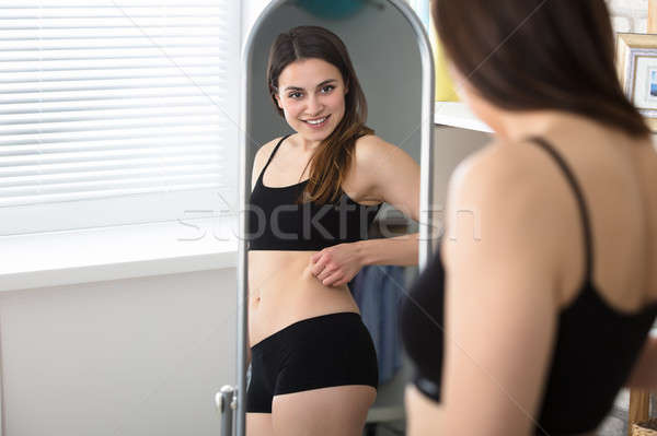Reflection Of Woman Pinches Fat On Her Belly Stock photo © AndreyPopov