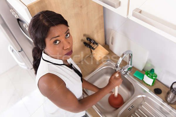 Unhappy Woman Using Plunger In Clogged Sink Stock photo © AndreyPopov