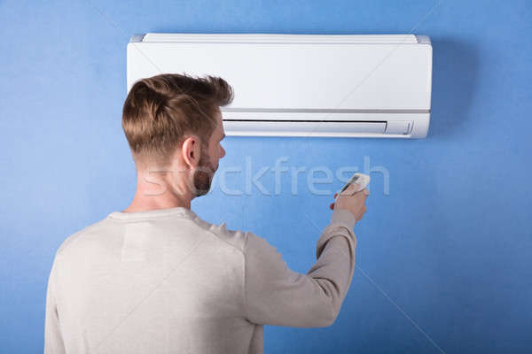 Rear View Of A Young Man Operating Air Conditioner Stock photo © AndreyPopov