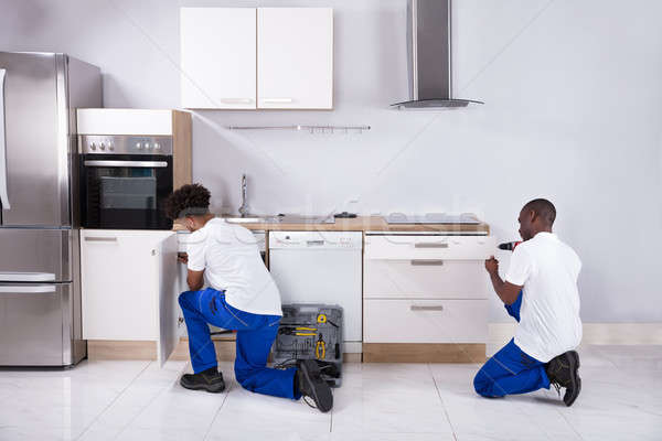 Two Handy Men Fixing The Wooden Cabinet In The Kitchen Stock photo © AndreyPopov