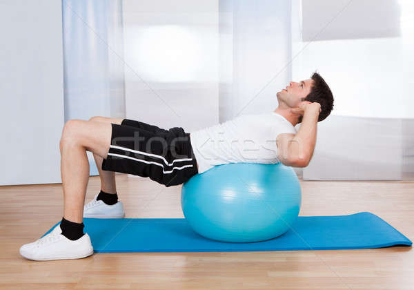 Man Doing Sit Ups On Fitness Ball Stock photo © AndreyPopov