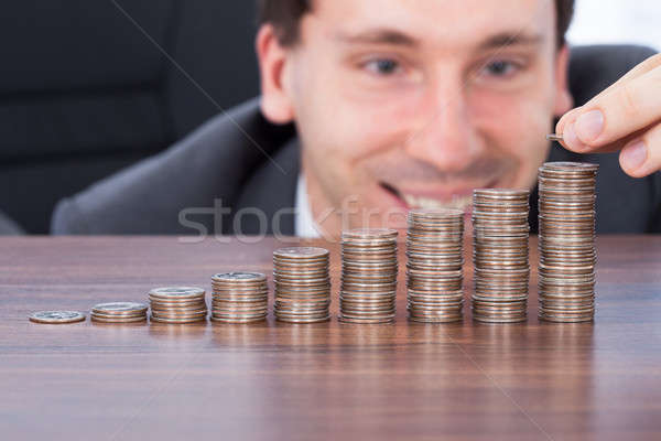 Happy Businessman Stacking Coins At Desk Stock photo © AndreyPopov