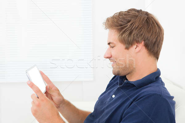 Stockfoto: Glimlachend · man · smartphone · home · volwassen · ontspannen