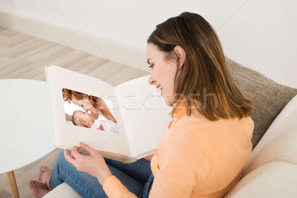Mosolygó nő néz fényképalbum mosolyog fiatal nő nappali Stock fotó © AndreyPopov