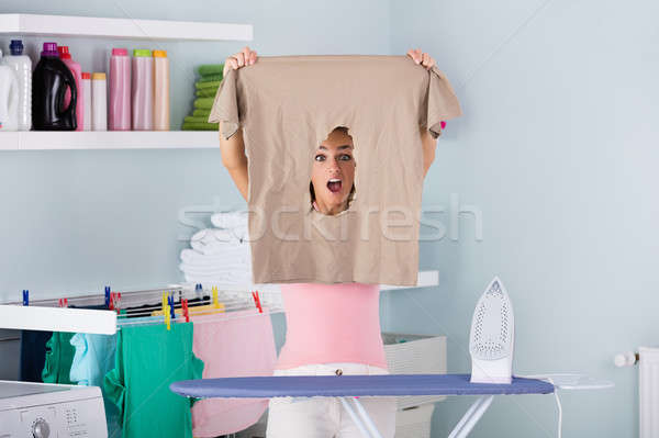 Shocked Woman Looking Through Burned Iron Cloth Stock photo © AndreyPopov