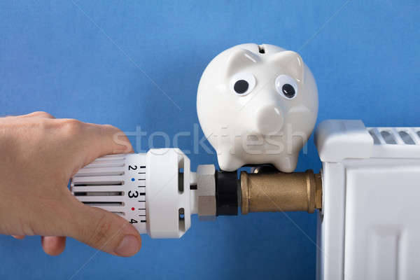 Mano termostato primo piano salvadanaio radiatore soldi Foto d'archivio © AndreyPopov
