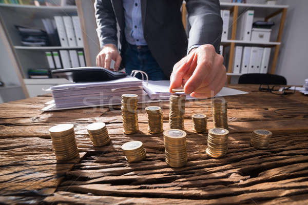 Businessperson Calculating Stacked Coins Stock photo © AndreyPopov